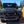 Load image into Gallery viewer, Front view of a black off-road vehicle with a clear sky and trees in the background
