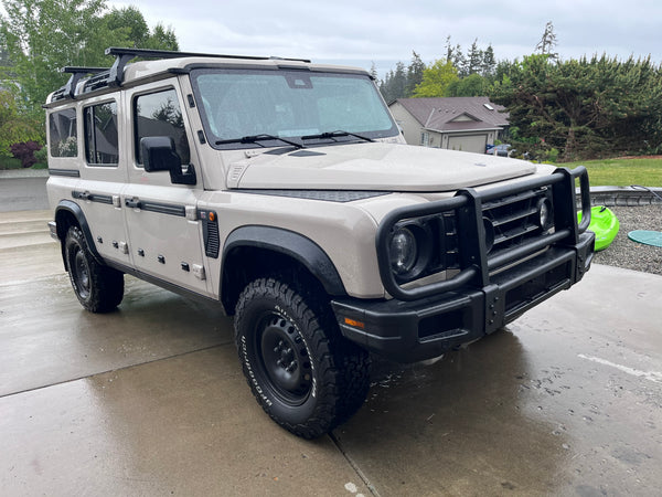 White off-road vehicle with roof rack on a wet driveway